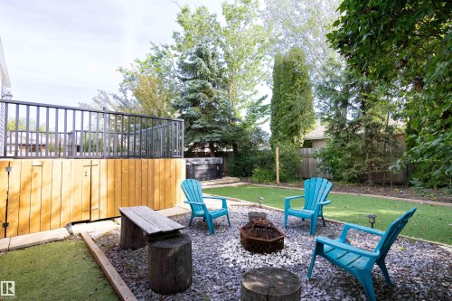 Expansive outdoor living area featuring a raised deck with dark railings, a hot tub, and a fire pit area with gravel hardscaping - 4903 11A Avenue Nw, Edmonton, AB - Outdoor With Deck Patio Veranda With Backyard