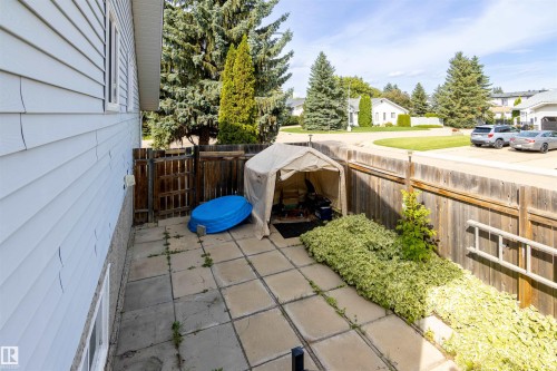Paved patio area featuring a wooden fence and established perimeter landscaping - 4903 11A Avenue Nw, Edmonton, AB - Outdoor