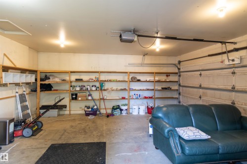 Attached garage featuring overhead lighting, built-in shelving, and a roll-up garage door - 4903 11A Avenue Nw, Edmonton, AB - Indoor Photo Showing Garage