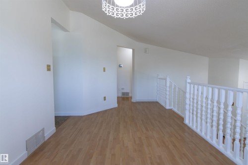 Bright interior featuring wood-finish flooring, white walls, and a white spindle railing - 4903 11A Avenue Nw, Edmonton, AB - Indoor Photo Showing Other Room