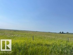 Expansive parcel featuring open fields and distant tree lines under a clear sky - 