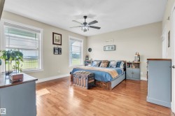 Spacious room featuring wood-finish flooring, light neutral walls, and a ceiling fan with integrated lighting - 