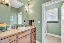 Bathroom vanity featuring a vessel sink, a multi-tone tile backsplash, and wood-finish cabinetry - 