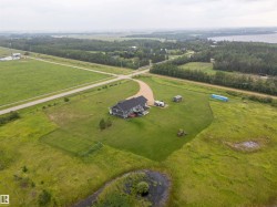 Spacious rural property featuring a modern gray exterior residence, expansive green grounds, and a gravel driveway - 