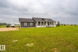 Single-story home featuring dark gray siding and a contrasting white foundation - 