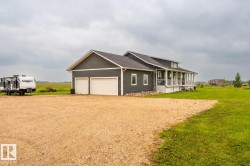 Single-story home featuring dark gray siding, a white columned porch, and a two-car garage with white doors - 