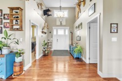 Inviting entryway featuring wood-finish flooring, a vaulted ceiling with an overhead light fixture, and a white front door with transom windows - 