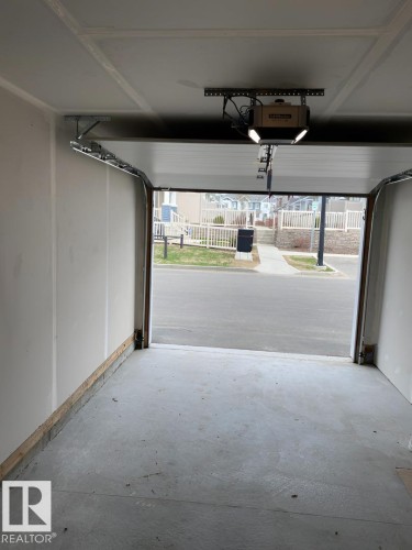Attached garage with concrete flooring, automatic garage door opener, and integrated lighting - #3 2905 141 St Sw, Edmonton, AB - Indoor Photo Showing Garage