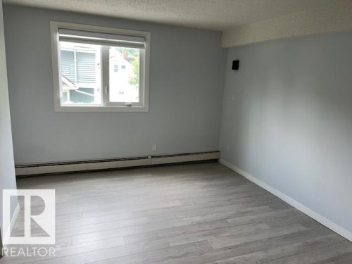 Wood-finish flooring, light gray wall color, white trim, and a window with roller shade - #202 9929 113 St Nw, Edmonton, AB - Indoor Photo Showing Other Room