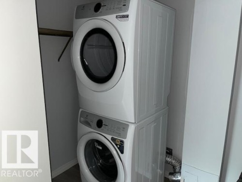 Stackable laundry appliances with a built-in shelving unit - #202 9929 113 St Nw, Edmonton, AB - Indoor Photo Showing Laundry Room