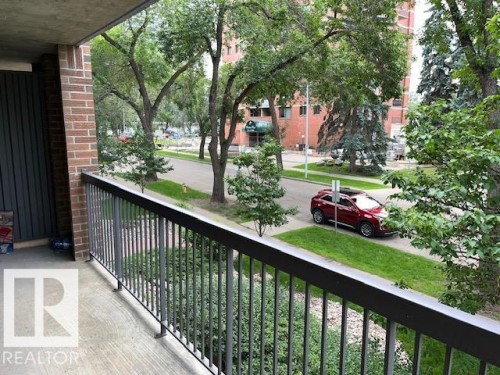 Private balcony with a metal railing, brick exterior column, and concrete flooring - #202 9929 113 St Nw, Edmonton, AB - Outdoor