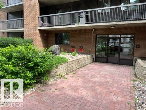Brick exterior building with glass entry doors, paver walkway, and terraced landscaping - #202 9929 113 St Nw, Edmonton, AB - Outdoor With Exterior