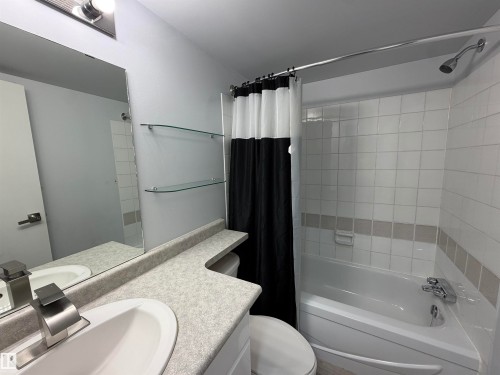 White tile bath surround, integrated bathtub, and vanity with an undermount sink - #202 9929 113 St Nw, Edmonton, AB 