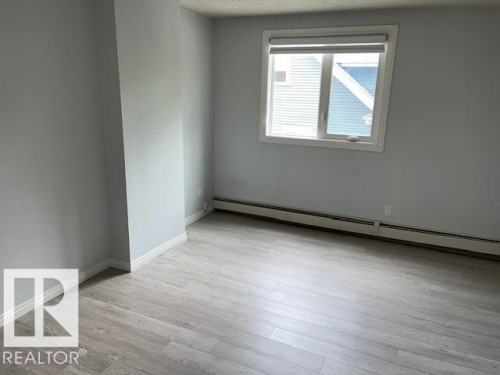 Wood-finish flooring, white window trim, and white baseboards - #202 9929 113 St Nw, Edmonton, AB - Indoor Photo Showing Other Room