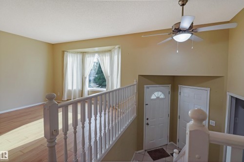 Upper-level landing featuring hardwood flooring, wooden stair railing with turned balusters, ceiling fan with integrated lighting, and access to multiple rooms - 1055 Jones Crescent Nw, Edmonton, AB - Indoor Photo Showing Other Room