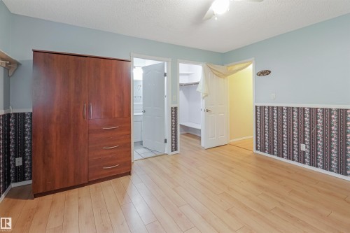 Wood-finish flooring, ceiling fan, and painted walls with accent wallpaper - 1055 Jones Crescent Nw, Edmonton, AB - Indoor Photo Showing Other Room