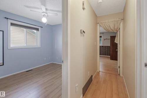 Wood-finish flooring throughout, light blue wall paint, white window trim, and a white ceiling fan with integrated lighting - 1055 Jones Crescent Nw, Edmonton, AB - Indoor Photo Showing Other Room