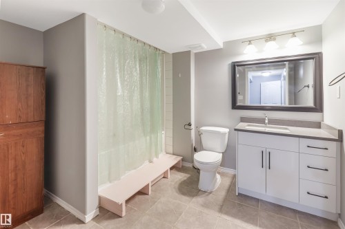 Spa-inspired primary bathroom featuring a frameless glass shower enclosure with tile surround, dual-sink vanity with soft-close cabinetry and brushed nickel hardware, ceramic tile flooring, and framed mirror with integrated lighting - 1055 Jones Crescent Nw, Edmonton, AB - Indoor Photo Showing Bathroom