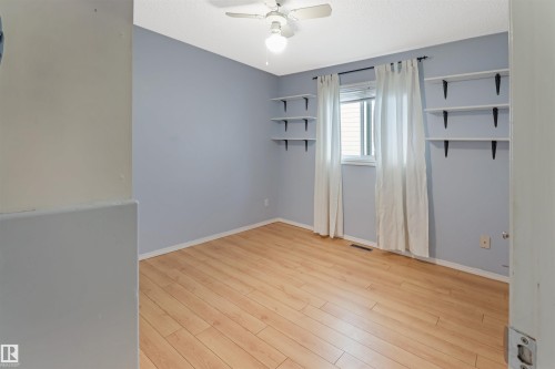 Bright and airy bedroom with fresh periwinkle walls, wood-finish flooring throughout, and abundant natural light from large windows dressed in neutral curtains - 1055 Jones Crescent Nw, Edmonton, AB - Indoor Photo Showing Other Room