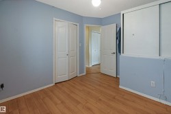 Spacious bedroom with soft blue walls, warm wood-finish flooring, and multiple closet options including mirrored sliding door storage - 