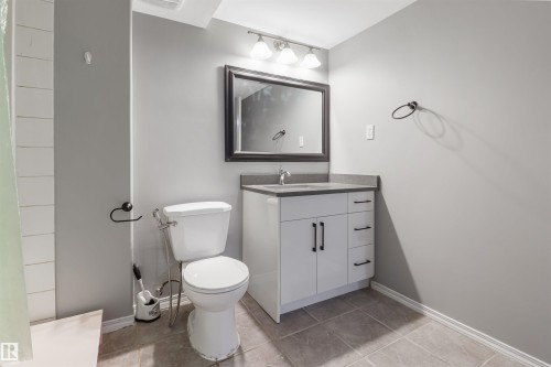 Modern bathroom featuring a two-piece toilet, vanity with multiple drawers and cabinet storage, quartz countertop, and brushed nickel fixtures - 1055 Jones Crescent Nw, Edmonton, AB - Indoor Photo Showing Bathroom