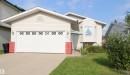 Exterior featuring light-colored siding, a prominent attached garage with decorative window inserts, a bay window with a small awning, and a concrete driveway - 1055 Jones Crescent Nw, Edmonton, AB  - Outdoor 