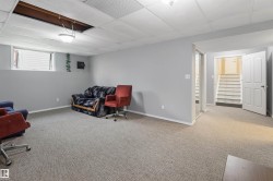 Spacious basement recreation room with neutral carpeting, recessed ceiling lighting, and abundant natural light from high-set windows - 