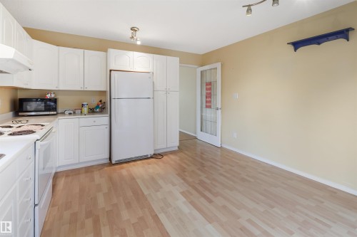 Kitchen featuring white cabinetry, wood-finish flooring, white appliances, and a track lighting fixture - 1055 Jones Crescent Nw, Edmonton, AB - Indoor Photo Showing Kitchen