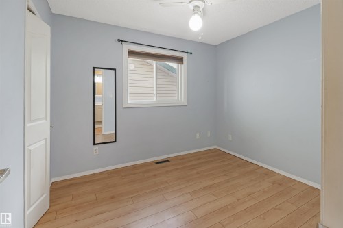 Light wood-finish flooring, a white ceiling fan with integrated lighting, and a window with blinds - 1055 Jones Crescent Nw, Edmonton, AB - Indoor Photo Showing Other Room