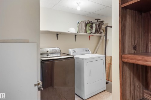 Dedicated laundry room featuring side-by-side washer and dryer appliances, overhead shelving with storage baskets, recessed ceiling lighting, and finished flooring throughout - 1055 Jones Crescent Nw, Edmonton, AB - Indoor Photo Showing Laundry Room