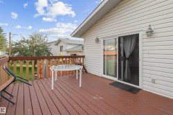 Expansive deck with wood-finish flooring, wood railing, and direct access to interior via sliding glass door - 