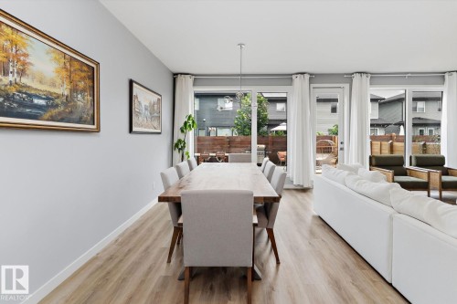 Wood-finish flooring throughout, light gray walls, multiple glass sliding doors, and a linear pendant light fixture - 3241 Kulay Way Sw, Edmonton, AB - Indoor