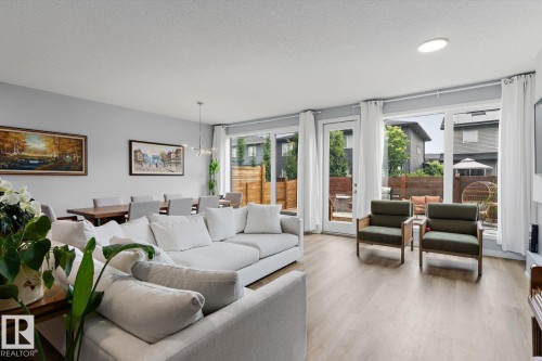 Open-concept living space with wood-finish flooring, a contemporary dining chandelier, and recessed ceiling lighting - 3241 Kulay Way Sw, Edmonton, AB - Indoor Photo Showing Living Room