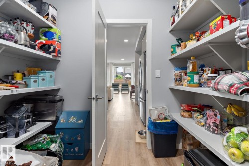Spacious pantry featuring multiple white shelving units and light wood-finish flooring - 3241 Kulay Way Sw, Edmonton, AB - Indoor With Storage