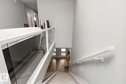 Staircase with carpeted treads and a white handrail, featuring a glass panel railing on the upper level - 3241 Kulay Way Sw, Edmonton, AB - Indoor Photo Showing Other Room