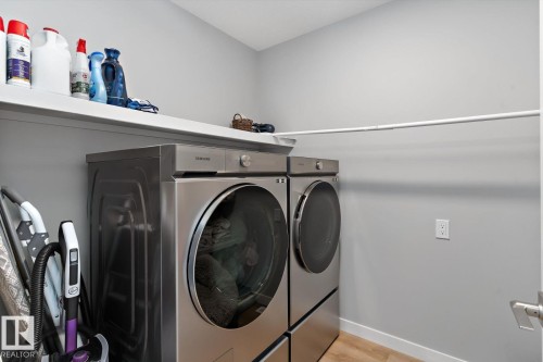 Built-in shelving with a hanging rod, light-toned wall paint, and wood-finish flooring - 3241 Kulay Way Sw, Edmonton, AB - Indoor Photo Showing Laundry Room