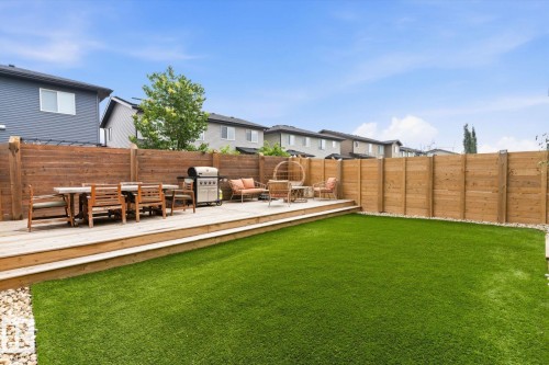 Expansive backyard featuring a large wooden deck, artificial turf, and privacy fencing - 3241 Kulay Way Sw, Edmonton, AB - Outdoor With Deck Patio Veranda