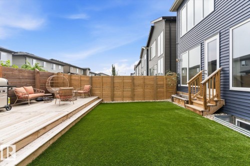 Expansive artificial turf lawn, multi-level wooden deck, private wood fence, and a modern exterior with large windows - 3241 Kulay Way Sw, Edmonton, AB - Outdoor With Deck Patio Veranda