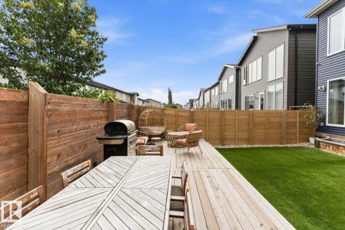 Spacious backyard featuring a wood deck, artificial turf, and privacy fencing - 3241 Kulay Way Sw, Edmonton, AB - Outdoor With Deck Patio Veranda