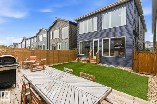 Expansive backyard featuring a wood deck, manicured lawn, and privacy fencing - 3241 Kulay Way Sw, Edmonton, AB - Outdoor With Deck Patio Veranda