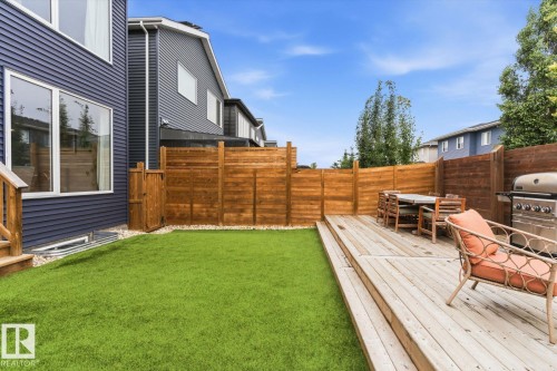 Expansive backyard featuring a wood deck with steps, artificial turf, and a wood fence enclosing the space - 3241 Kulay Way Sw, Edmonton, AB - Outdoor With Deck Patio Veranda
