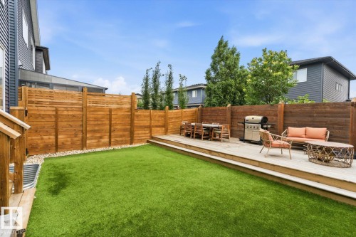 Expansive backyard featuring a tiered wood deck, natural wood privacy fencing, and artificial turf - 3241 Kulay Way Sw, Edmonton, AB - Outdoor With Deck Patio Veranda
