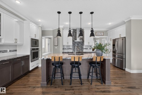 Kitchen featuring a large island with stone countertop, stainless steel appliances, wood-finish flooring, and pendant lighting - 1399 Graydon Hill Way Sw, Edmonton, AB - Indoor Photo Showing Kitchen With Upgraded Kitchen