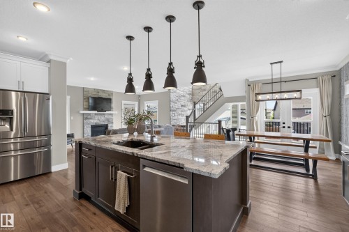 Kitchen island with stone countertop, dark wood-finish cabinetry, stainless steel appliances, and recessed lighting - 1399 Graydon Hill Way Sw, Edmonton, AB - Indoor Photo Showing Kitchen With Double Sink With Upgraded Kitchen