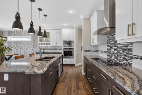 Kitchen featuring a large island with an undermount sink, pendant lighting, stainless steel appliances, and wood-finish flooring - 1399 Graydon Hill Way Sw, Edmonton, AB - Indoor Photo Showing Kitchen With Double Sink With Upgraded Kitchen