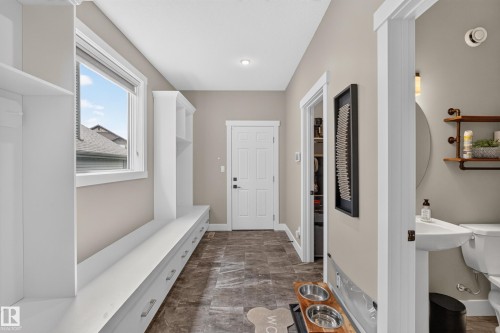 Built-in white cabinetry with storage bench, contemporary light fixture, pedestal sink, and tiled flooring - 1399 Graydon Hill Way Sw, Edmonton, AB - Indoor Photo Showing Other Room