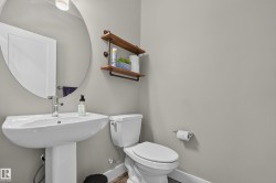 Pedestal sink with chrome faucet, round wall mirror, and wall-mounted shelving with pipe-style supports - 