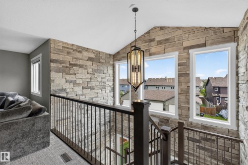 Stone accent wall with multiple windows, vaulted ceiling, and a decorative pendant light fixture - 1399 Graydon Hill Way Sw, Edmonton, AB -  With Exterior