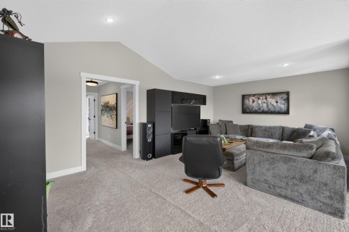 Vaulted ceiling, recessed lighting, neutral wall tones, built-in entertainment center, and carpeted flooring - 1399 Graydon Hill Way Sw, Edmonton, AB - Indoor