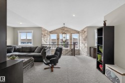 Carpeted loft space featuring an exposed stone accent wall, vaulted ceiling, and built-in shelving - 